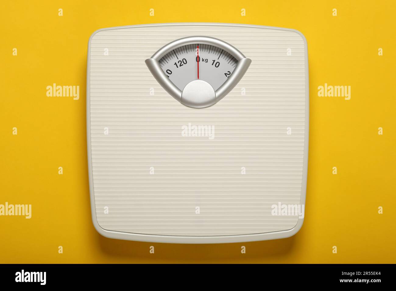Weigh scales on yellow background, top view. Overweight concept Stock Photo