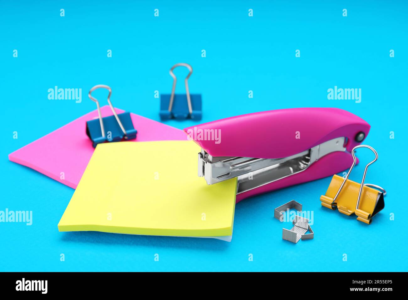 New bright stapler with blinder clips and sticky notes on light