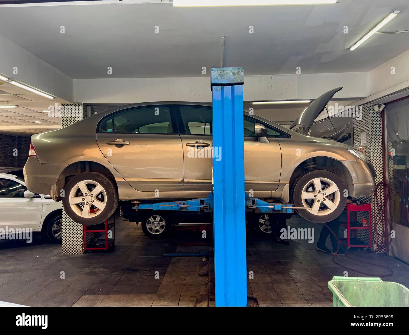 Car on lift, side view. Car repair shop concept: Automobile service interior background with cars on lift. Maintenance costs. Car accident insurance. Stock Photo