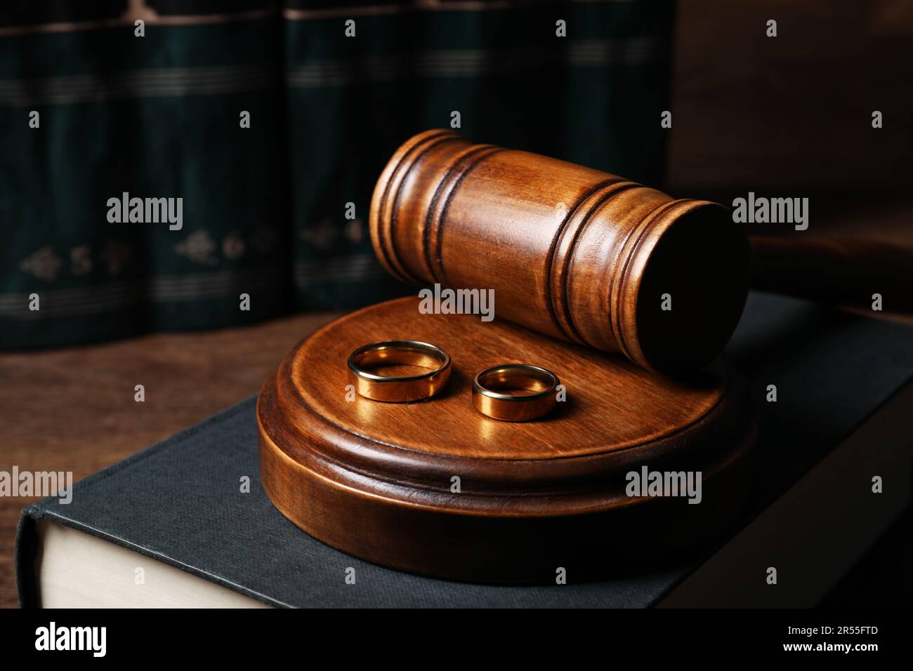 Divorce concept. Gavel, wedding rings and book on wooden table, closeup Stock Photo