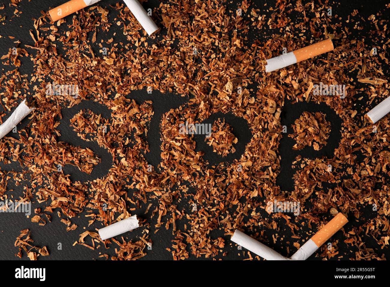 Word Stop made of dry tobacco and broken cigarettes on dark grey  background, flat lay. Quitting smoking concept Stock Photo