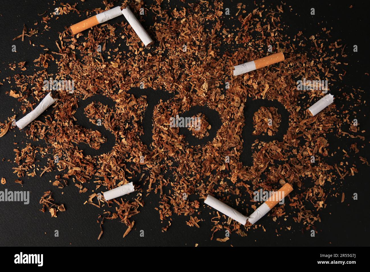 dry smoking cigarette Word Stop made of dry tobacco and broken cigarettes on dark grey  background, flat lay. Quitting smoking concept Stock Photo