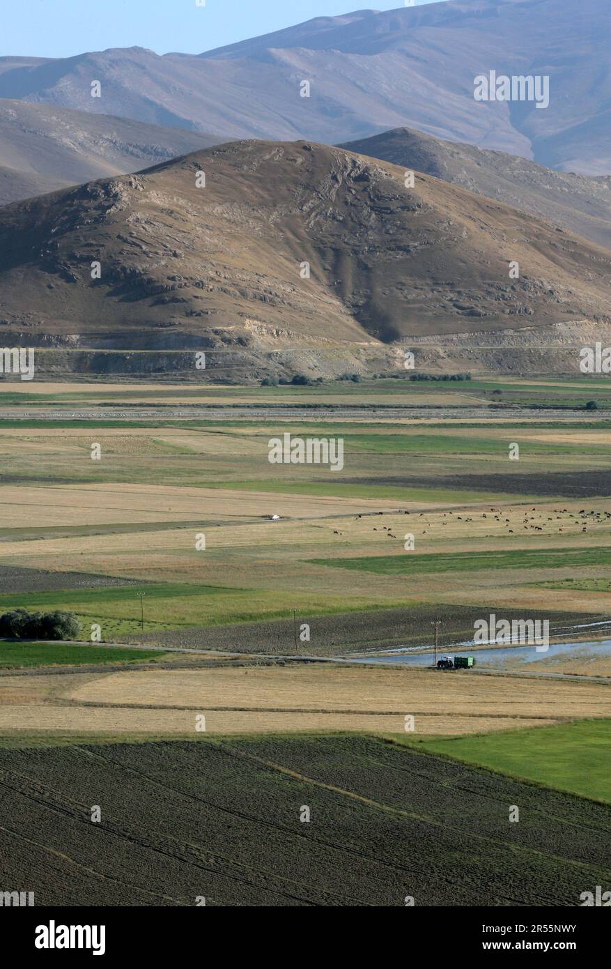 A view of farm land sitting below barren mountains at Cavustepe in the Gurpinar district of Van Province in eastern Turkiye. Stock Photo
