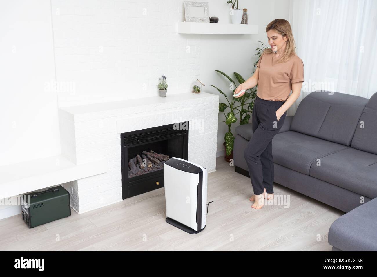 Woman using air purifier, dust filter, clean and health air Stock Photo