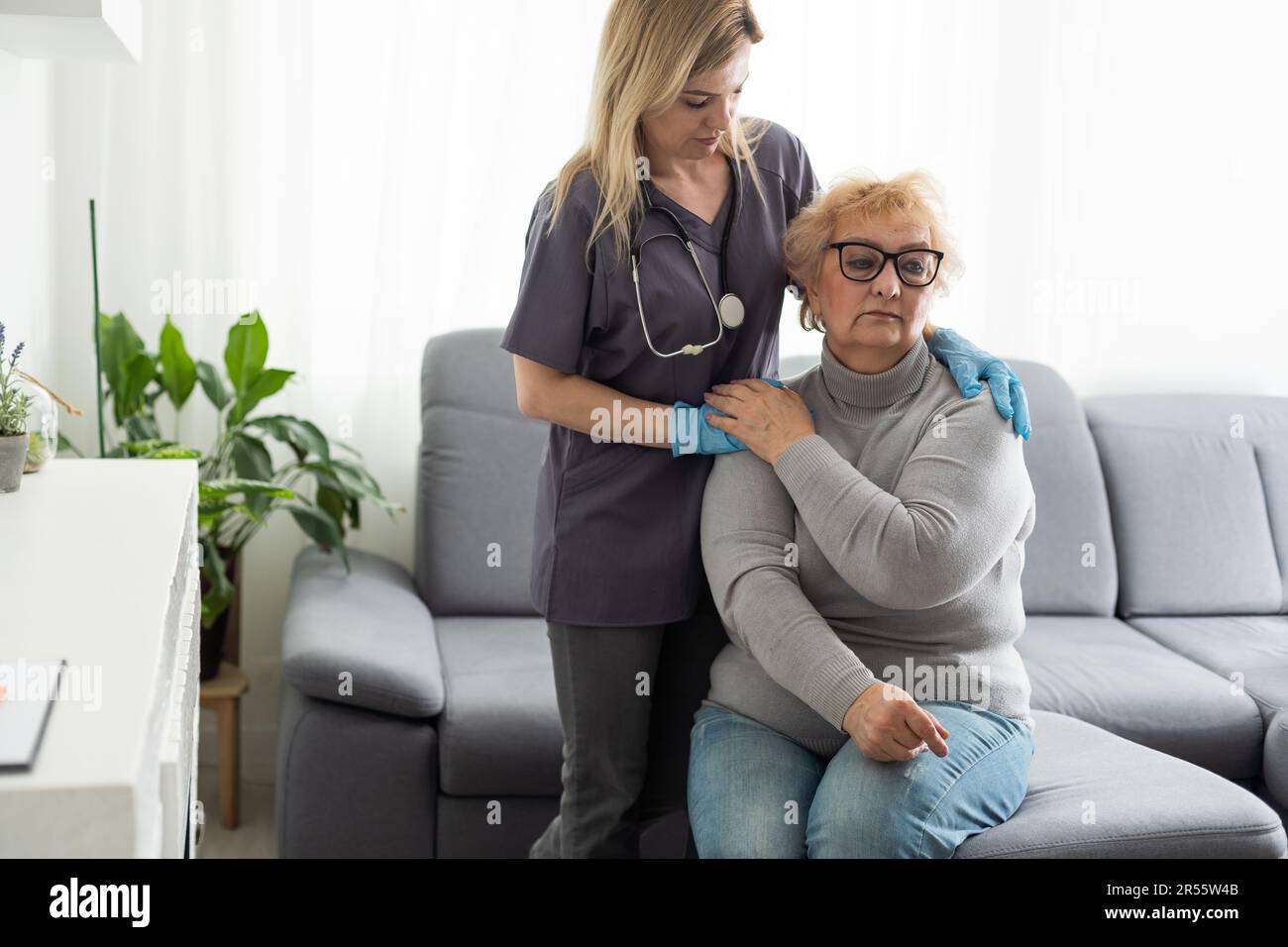 Caring young nurse doctor carer helping holding hands of happy disabled handicapped or injured old adult elder woman having disability health problem Stock Photo