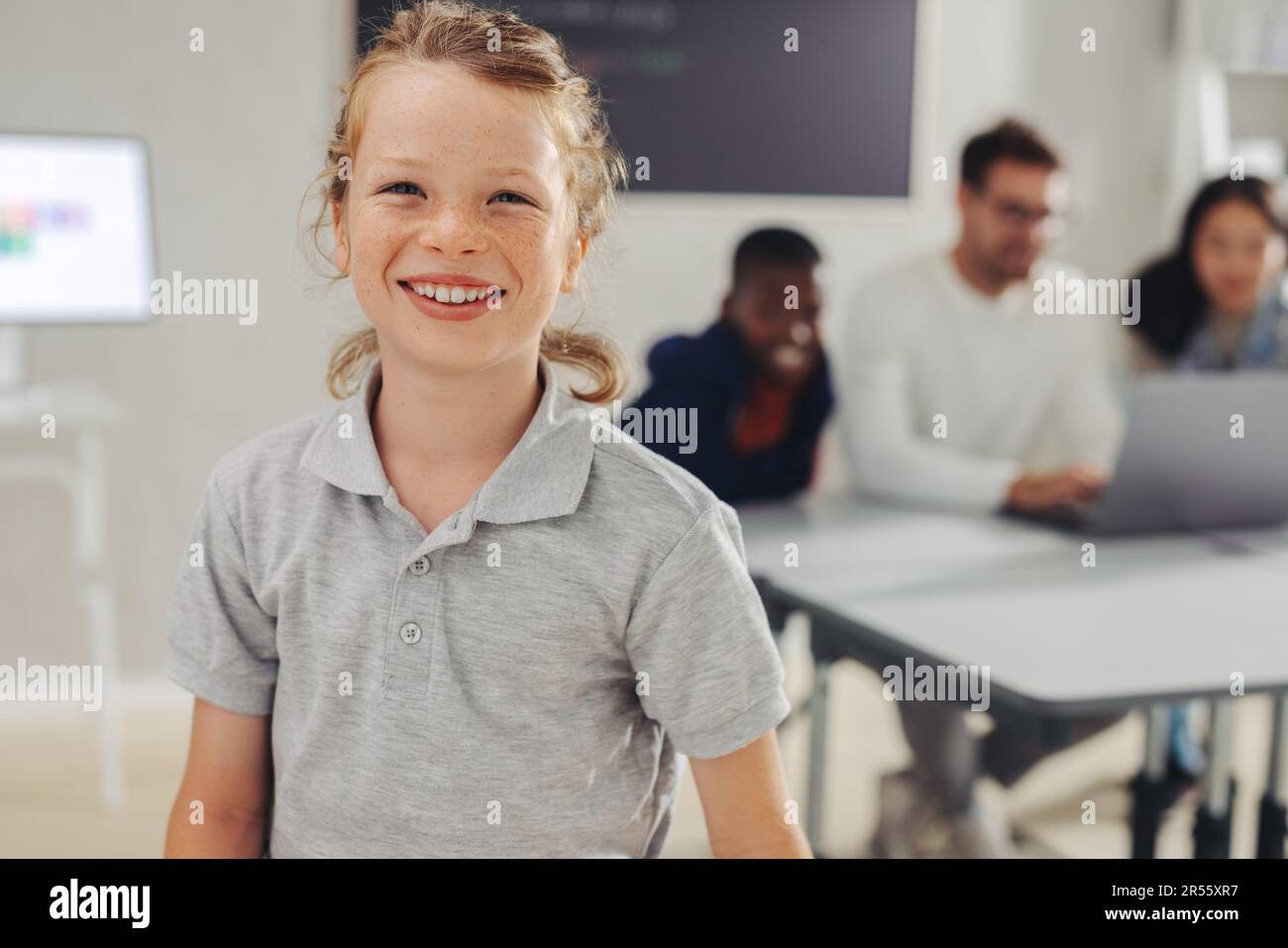 Young male student standing in a coding classroom, smiling at the camera with confidence. Young school boy showing excitement for a computer programmi Stock Photo