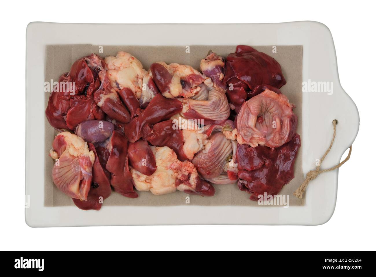 Raw chicken giblets on a ceramic board isolated on white background. Chicken stomachs, hearts and livers are prepared for cooking. Stock Photo