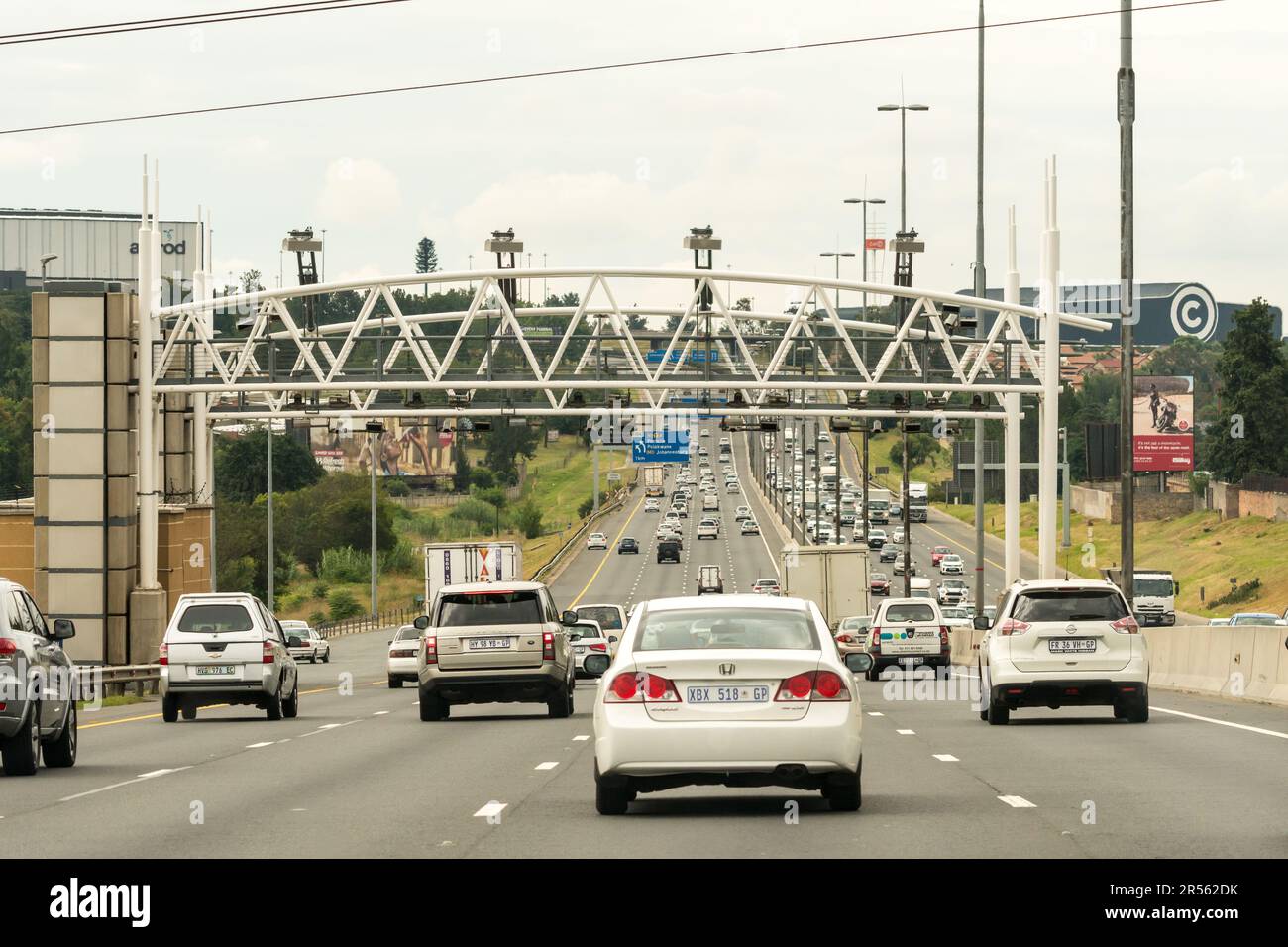 cars, vehicles, motorists drive on a national road or highway under e toll gantries which collect e tolls or electronic tolls in Gauteng, South Africa Stock Photo