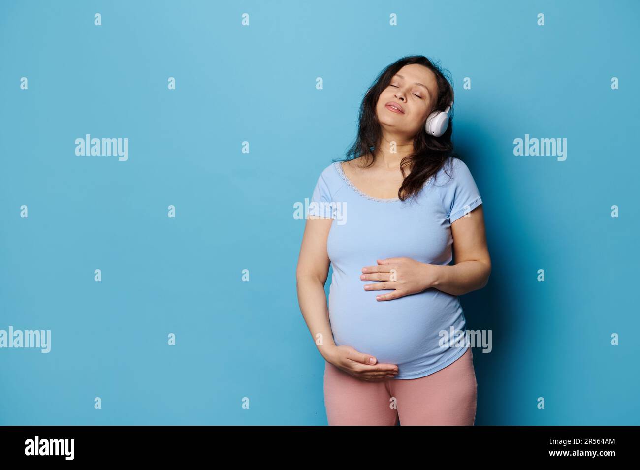 Future Mom holding headphones on her big belly, while her unborn baby  listening pleasant sounds and melody. First Child Anticipation Stock Photo  - Alamy