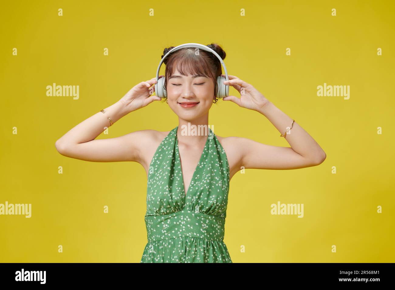 Happy Asian woman wearing headphones listening to music from smartphone ...