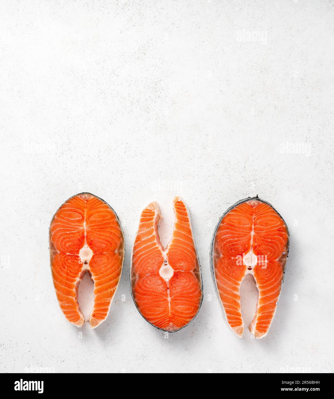Fresh raw salmon steaks on white concrete table. Top view of fish on ...
