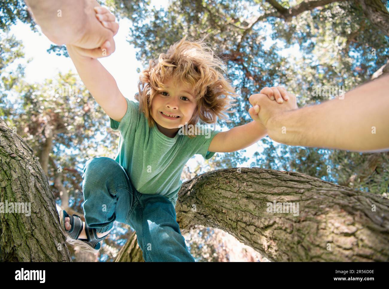 Father helping son to climb tree. Fathers hand. Child protection. Healthy parenting lifestyle. Stock Photo