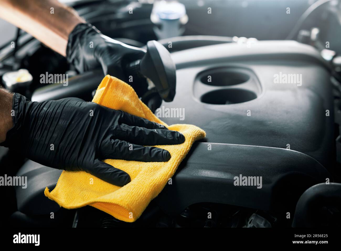 man cleaning car engine room with microfiber cloth and spray. auto