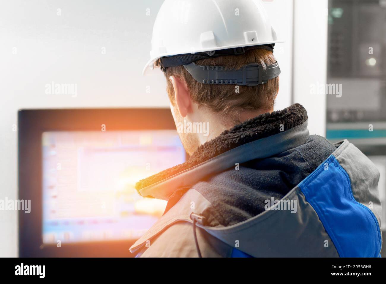 An engineer in a white helmet points to the touch screen of the natural ...