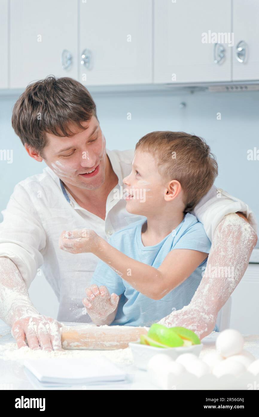 A young father and son are sitting at the kitchen table covered in