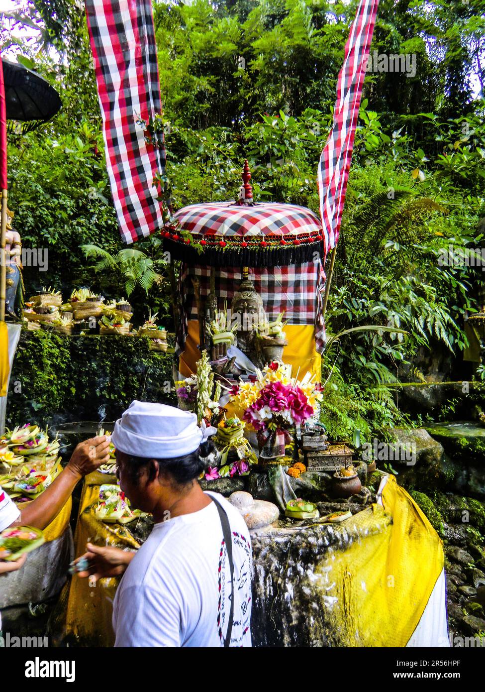 Bali Hinduism, devout people praying in Taman Beji Griya Waterfall with Brahmin priest in white robe, Bali, Indonesia Stock Photo