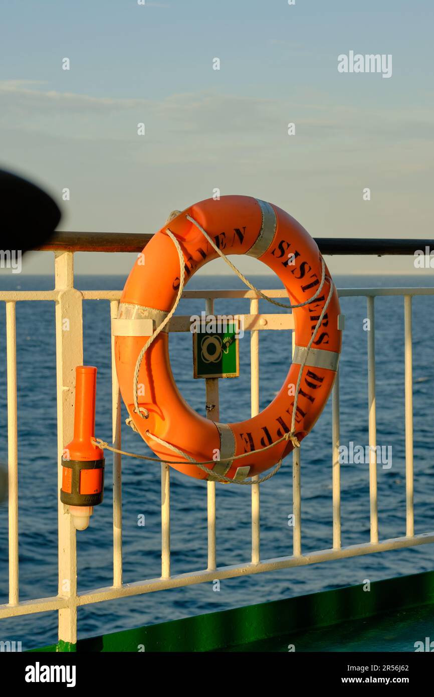 An orange lifebuoy on the railings of a passenger ferry at sea. Stock Photo