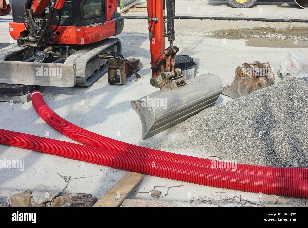 road works with plastic pipes for electric cables, gravel and excavator Stock Photo