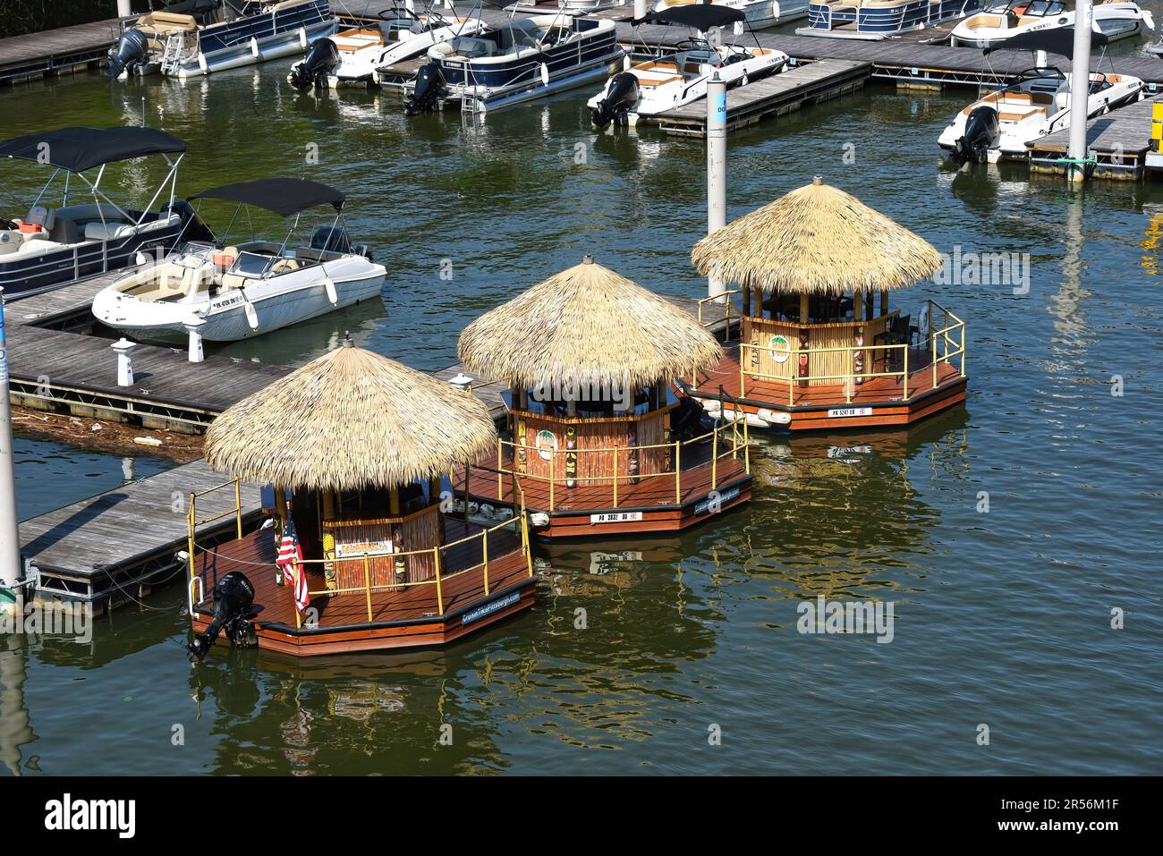 Pittsburgh, PA, USA- May 21, 2023: Three Cruisin’ Tiki boats docked on the Monongahela River. The fun boats can take six people on a two hour sightsee Stock Photo