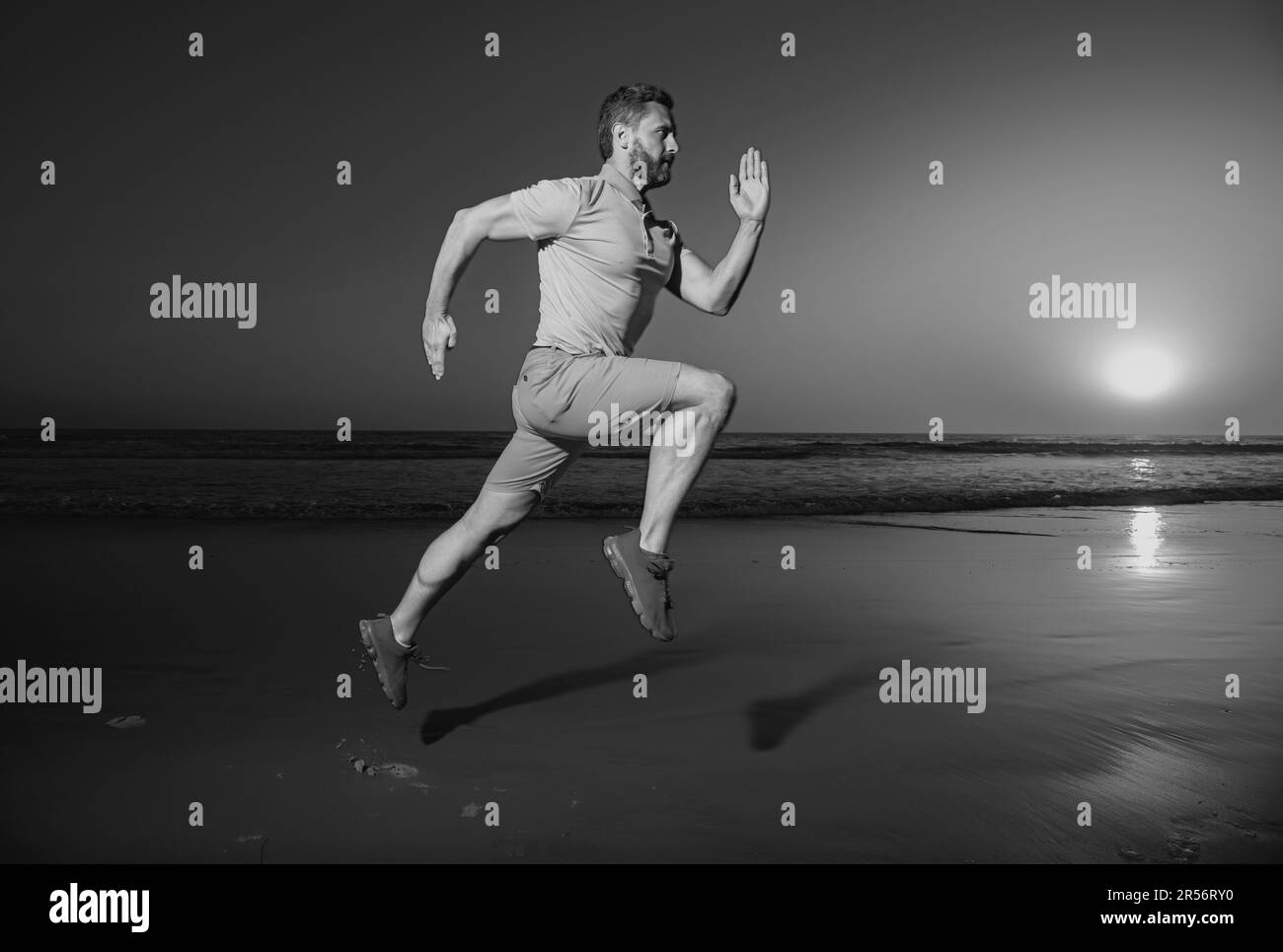 Sporty man runner running in summer sea beach. Attractive fit man run on sunset light, workout outdoors, jogging with amazing sunset on background. Stock Photo