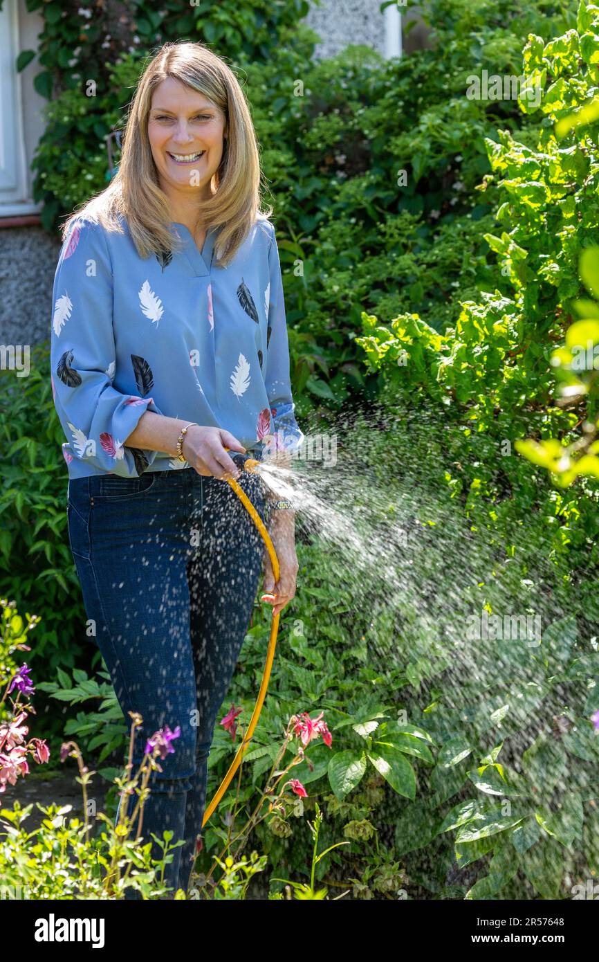 Woman watering garden with hose Stock Photo