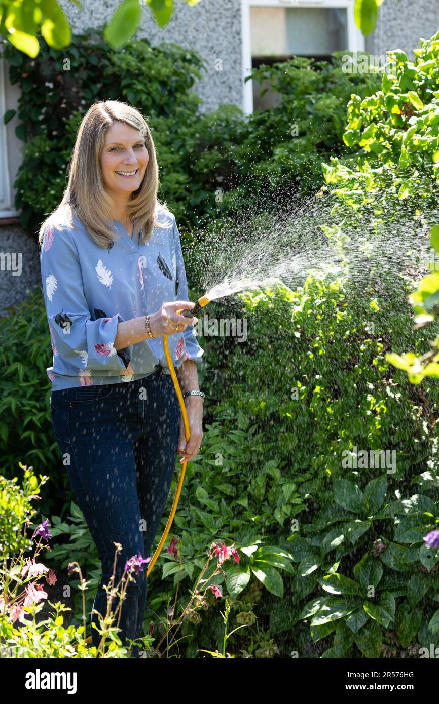 Woman watering garden with hose Stock Photo