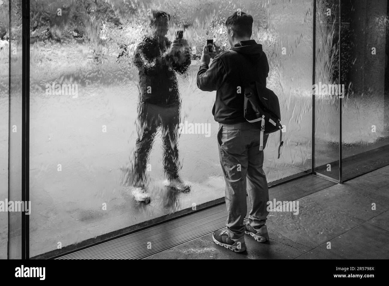 Visitors photograph each other through the Waterwall at the National Gallery of Victoria, Melbourne, Australia Stock Photo