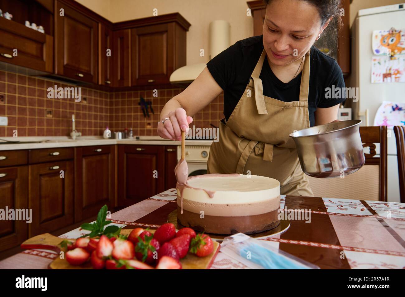 Pregnant female chef confectioner decorating with ruby pink glaze the