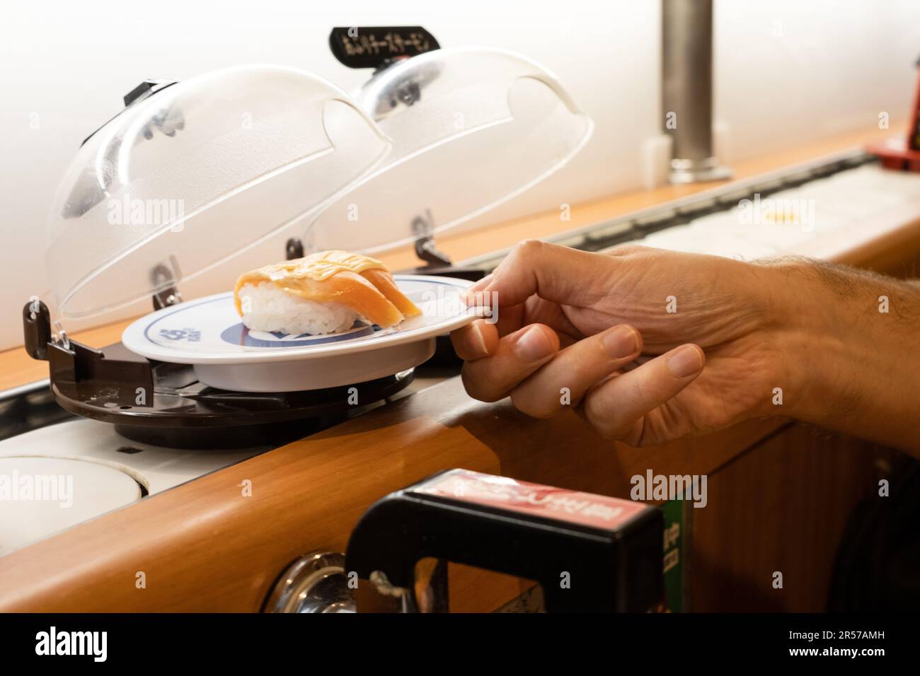 Hand selecting conveyor belt sushi at Kura Sushi, Japan Stock Photo