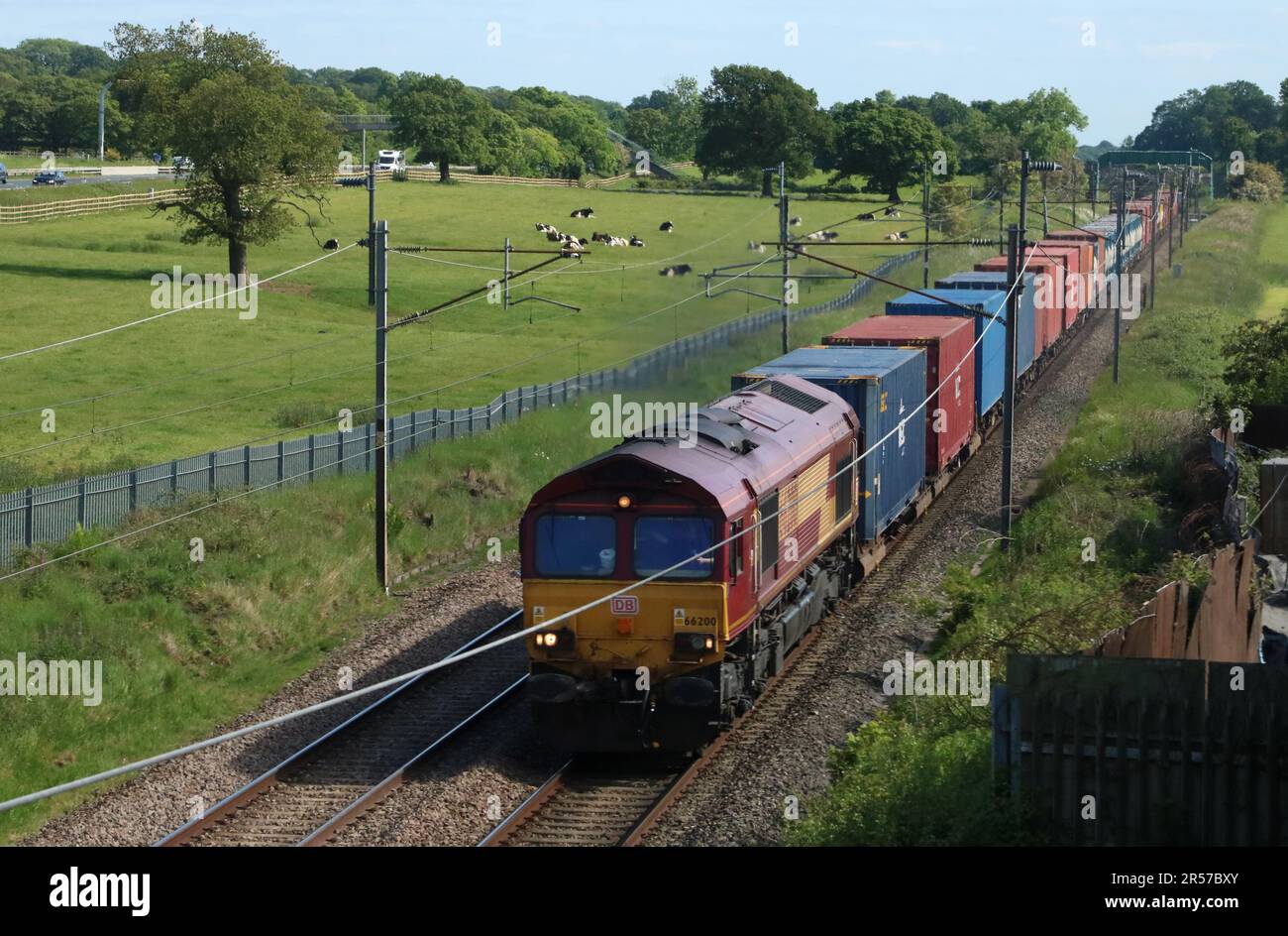 Class 66 diesel-electric shed locomotive on container train on West Coast Main line railway in countryside at Woodacre near Garstang, 1st June 2023. Stock Photo