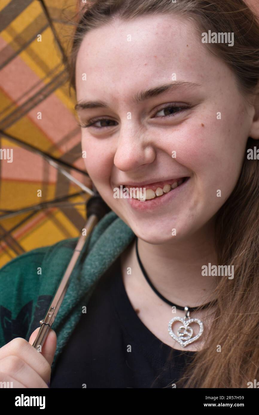 Teenage girl holding an umbrella with straight teeth after getting