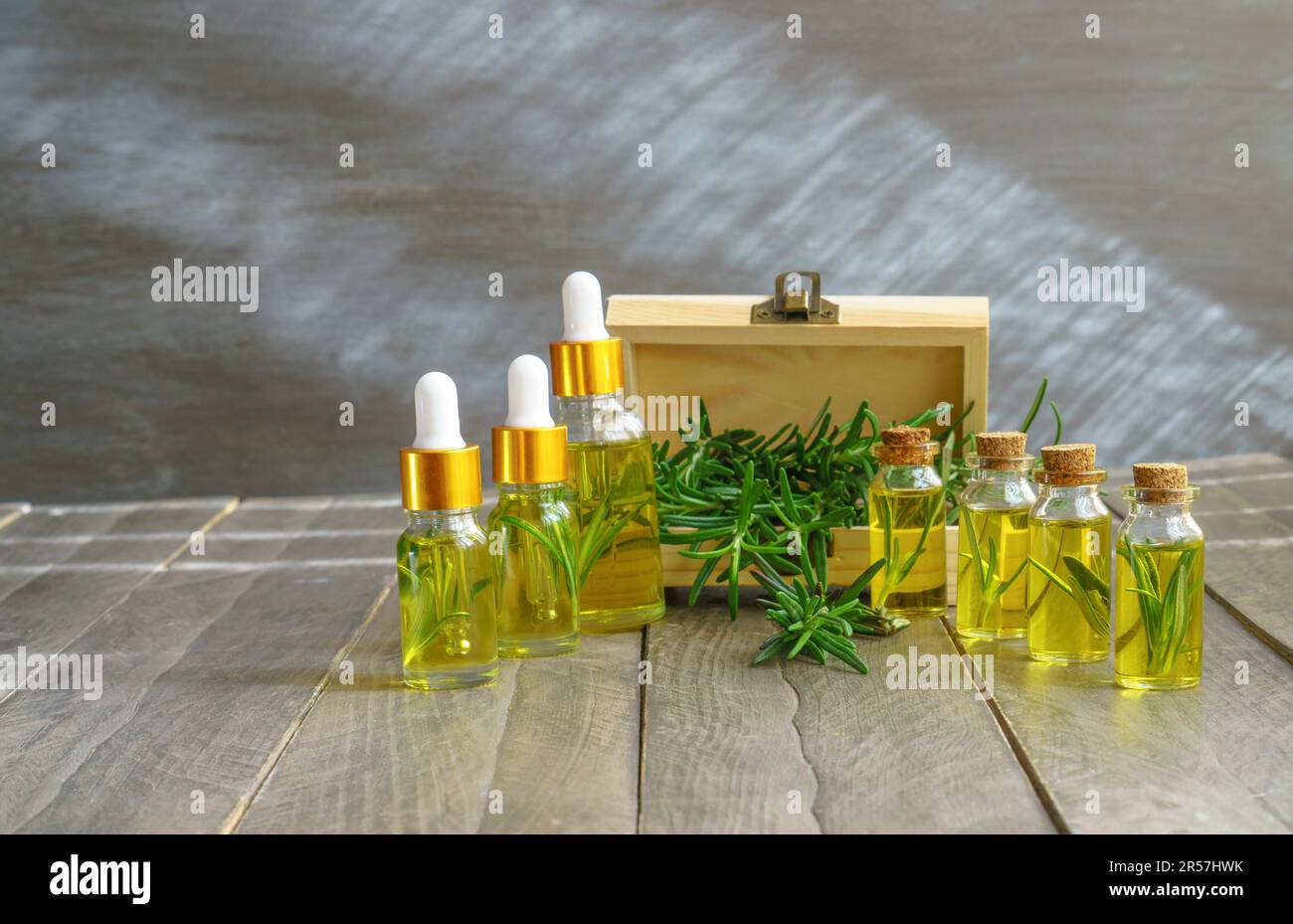 Bottles in a row with droppers of rosemary essential oil with a wooden
