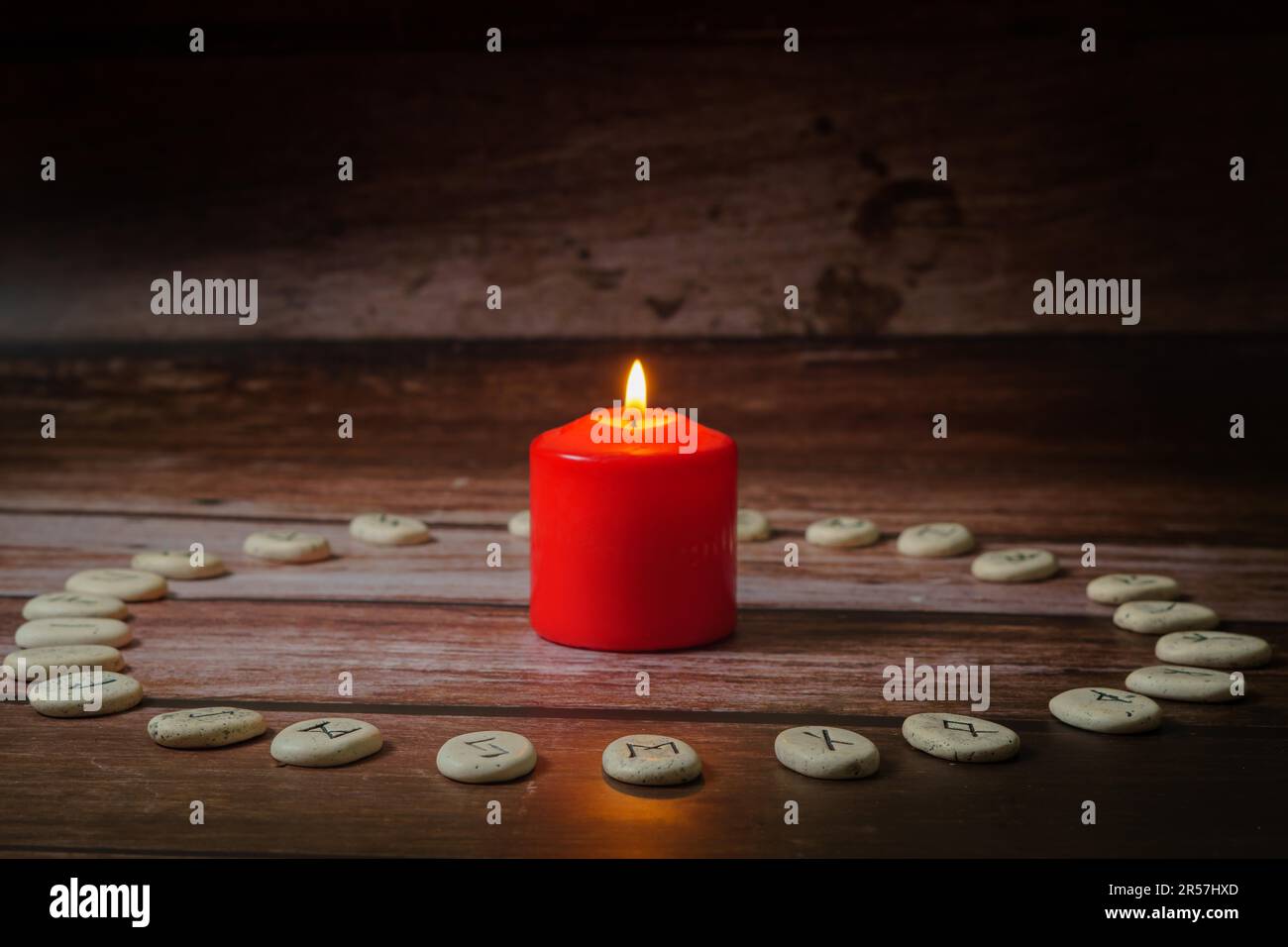 Circle of Viking stone runes on a wooden table with a lighted red