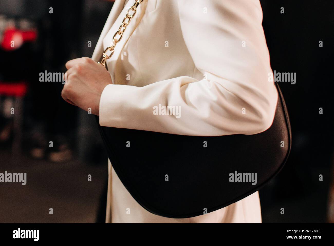 Fashion details of white classy jacket and black leather handbag with golden chain. Style, design of women's clothing and accessories. Stock Photo