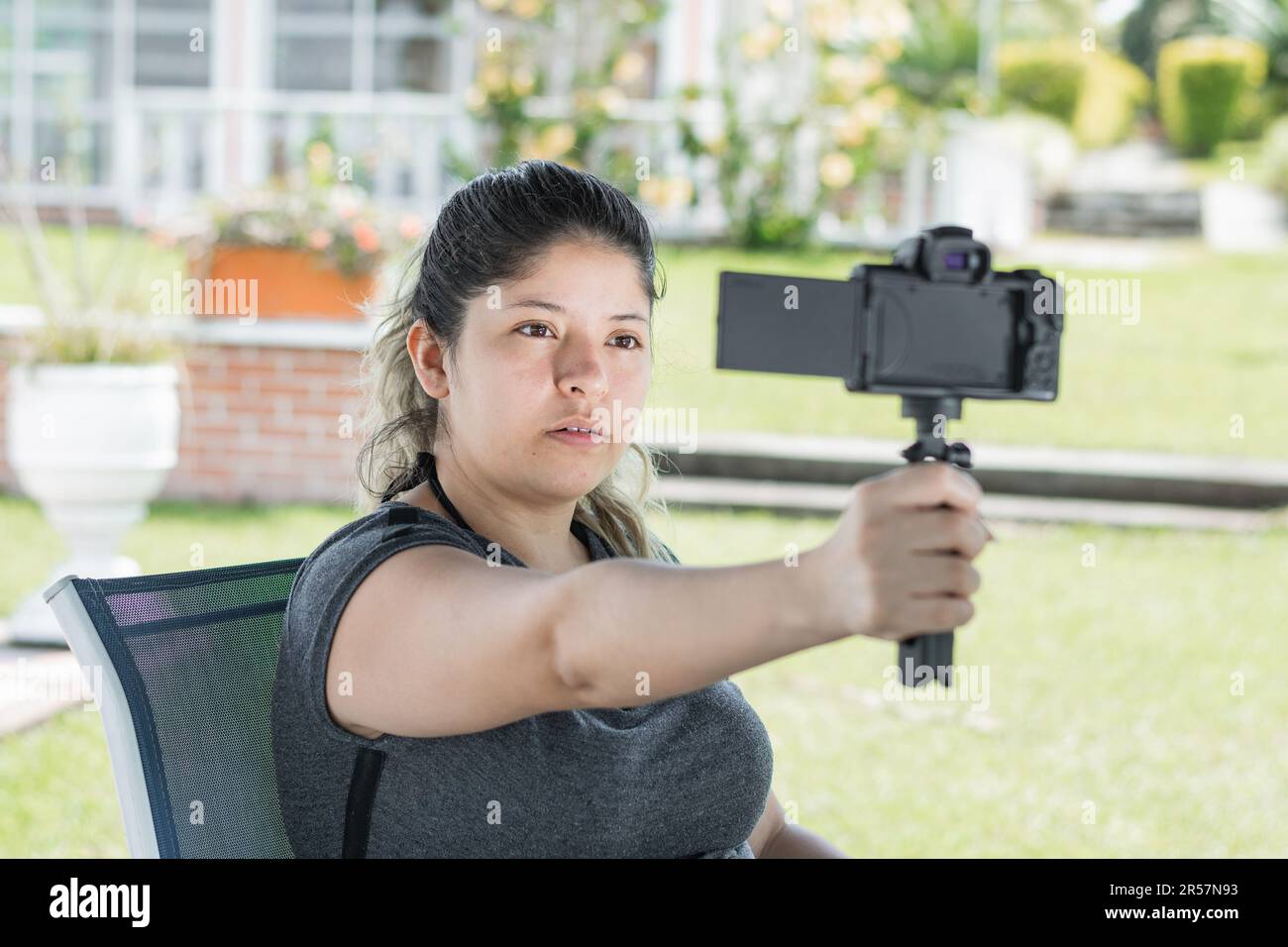 young latin influencer woman, filming herself with camera in hand 