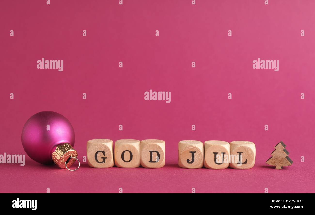 Small wooden blocks with the inscription God Jul, Scandinavian Merry Christmas, purple background, minimalist wooden Christmas decoration Stock Photo