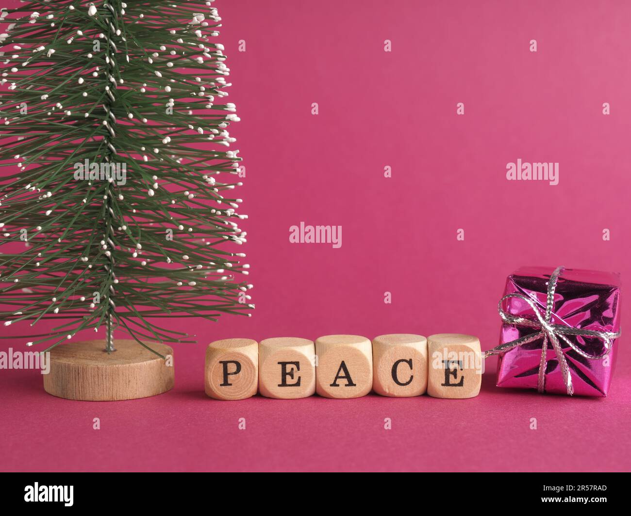 Small wooden blocks with the inscription peace, Merry Christmas, purple background, minimalist wooden Christmas decoration Stock Photo