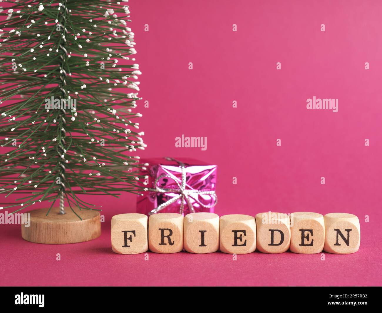 Small wooden blocks with the German inscription peace, Merry Christmas, purple background, minimalist wooden Christmas decoration Stock Photo