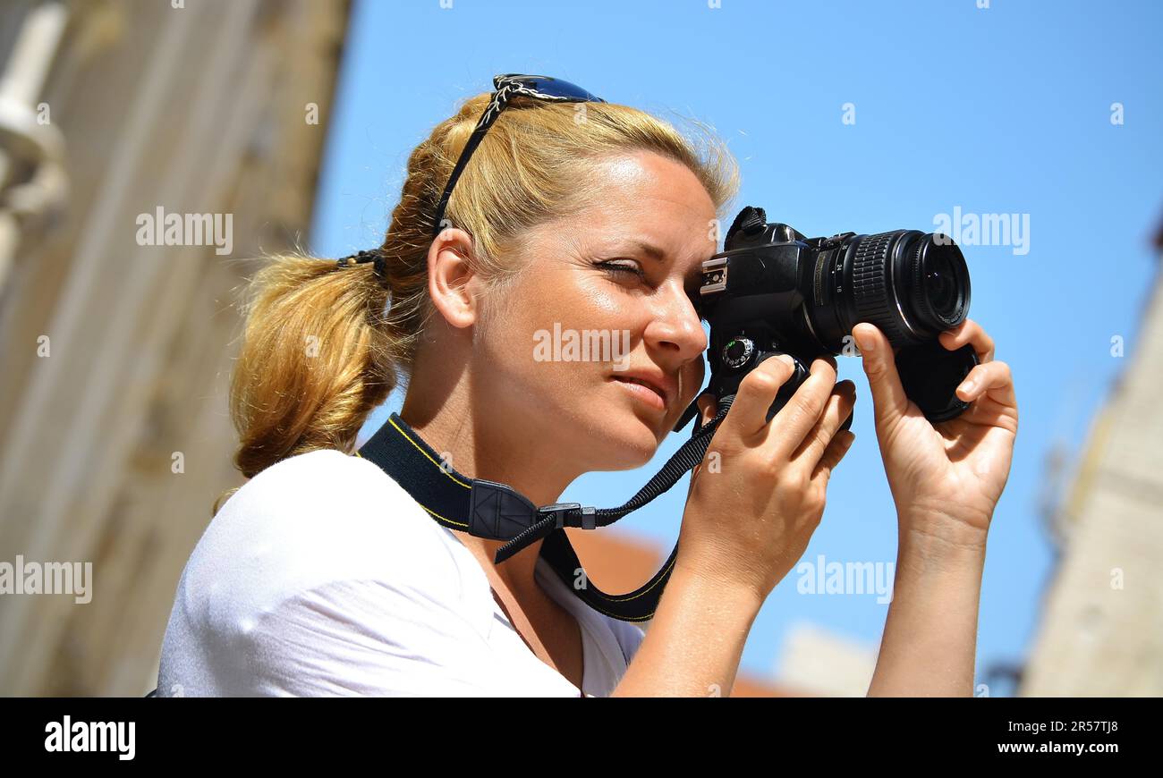Young female tourist visiting Mediterranean old town on vacation. Woman taking photos on the street Stock Photo