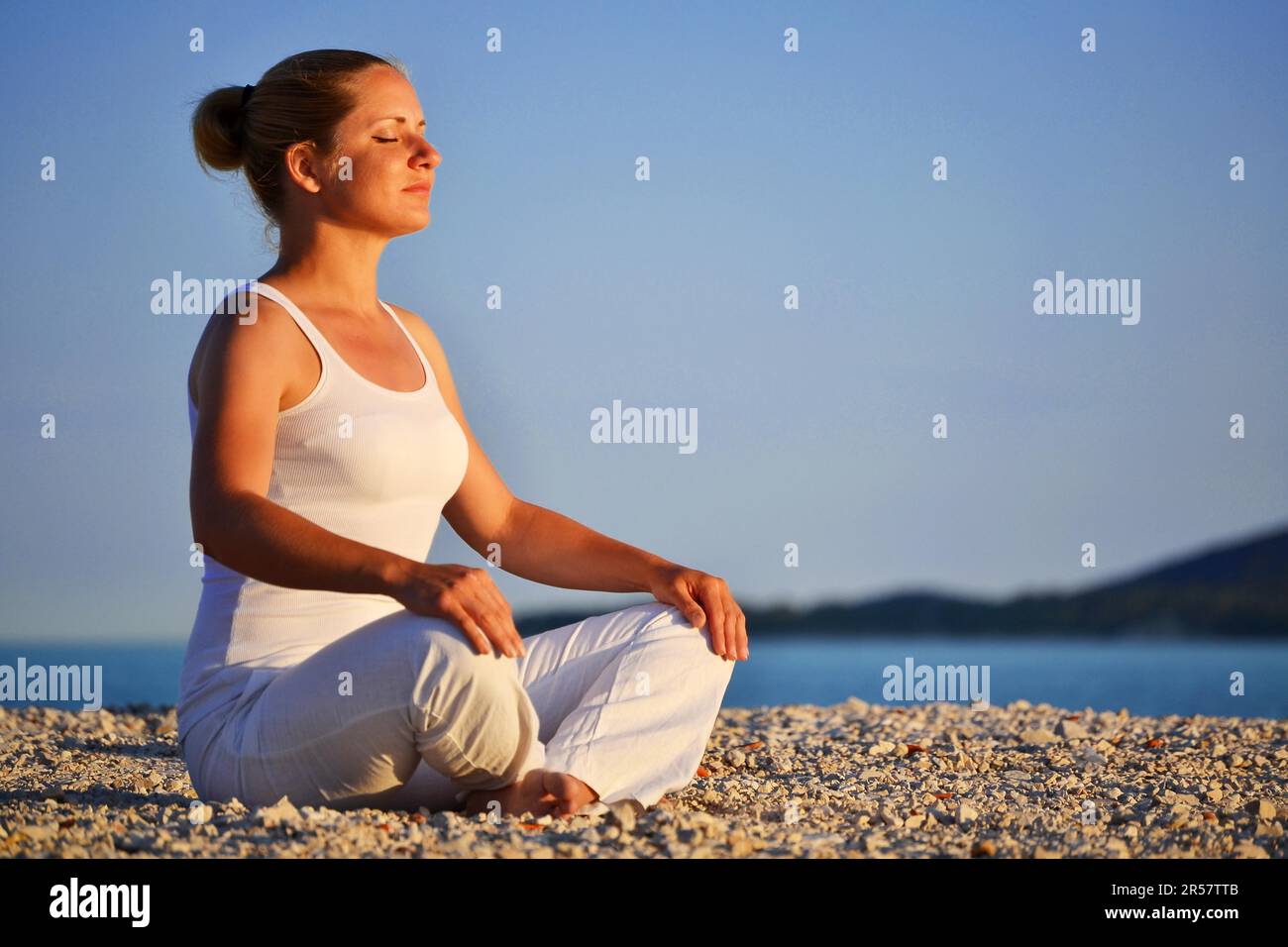 Young woman during yoga meditation on the beach Stock Photo - Alamy