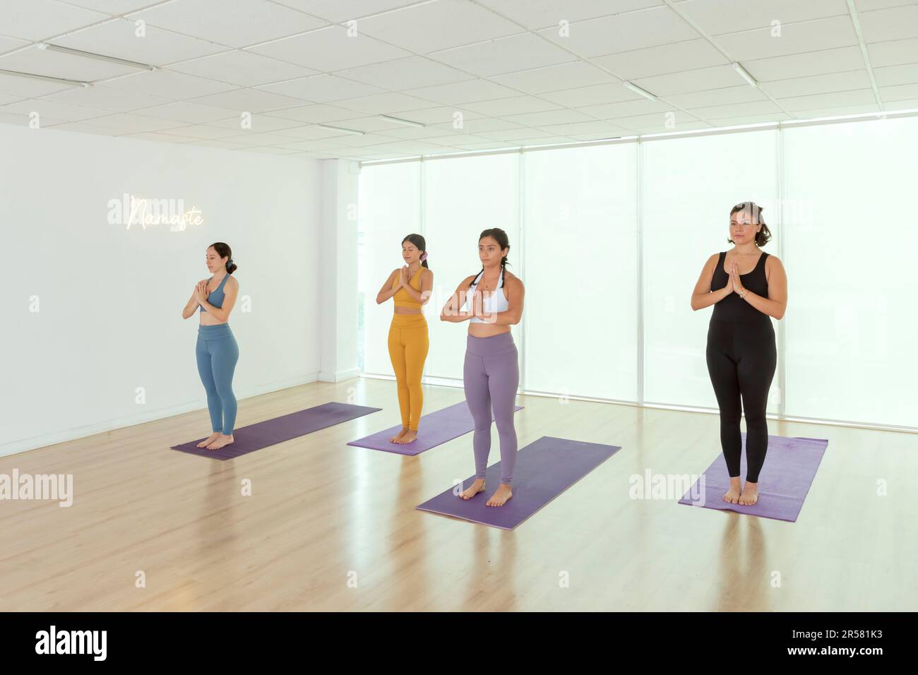 Yoga studio with a group of women training in it standing doing