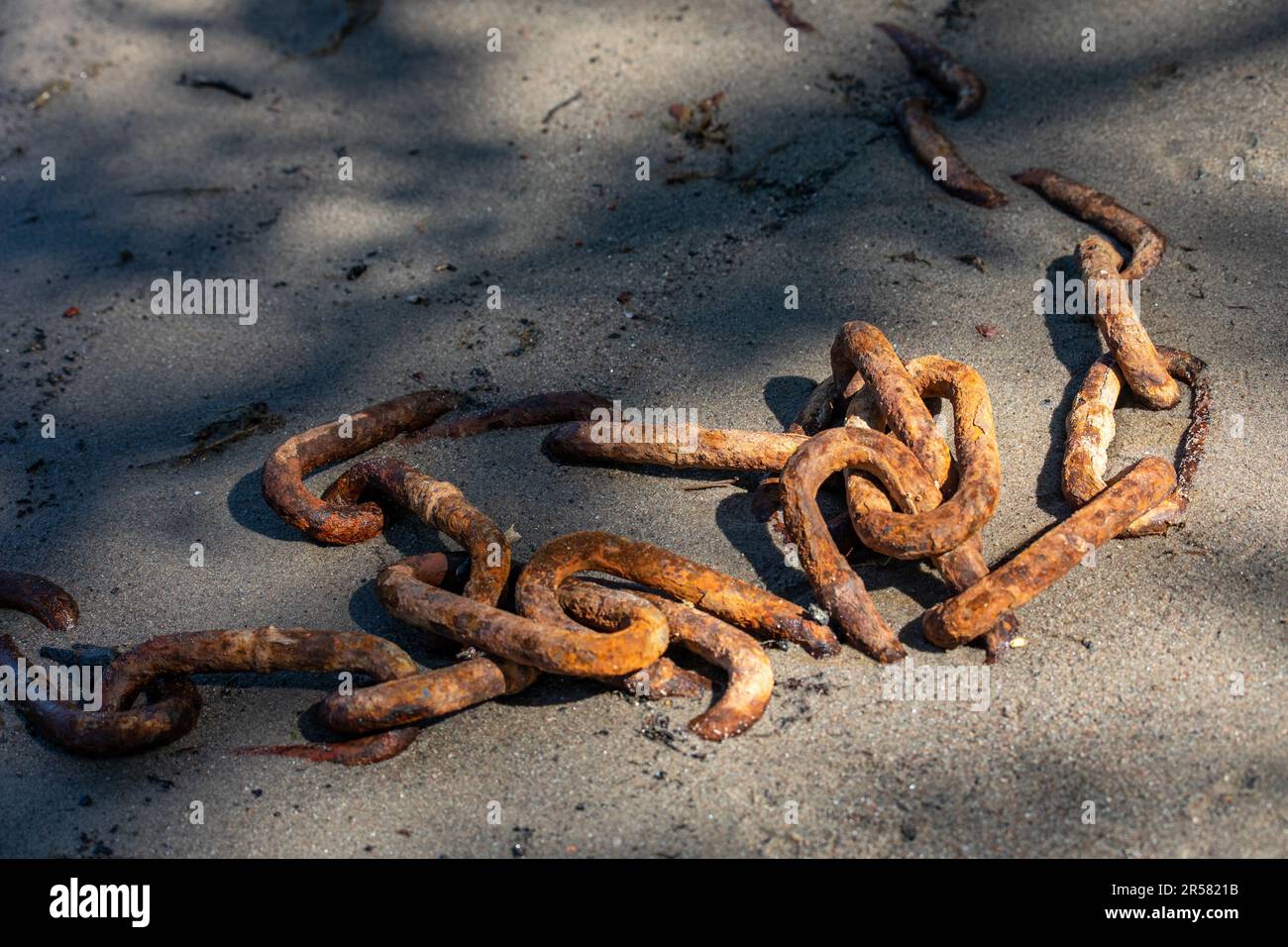 Rusty old chain half buried in the sand Stock Photo - Alamy