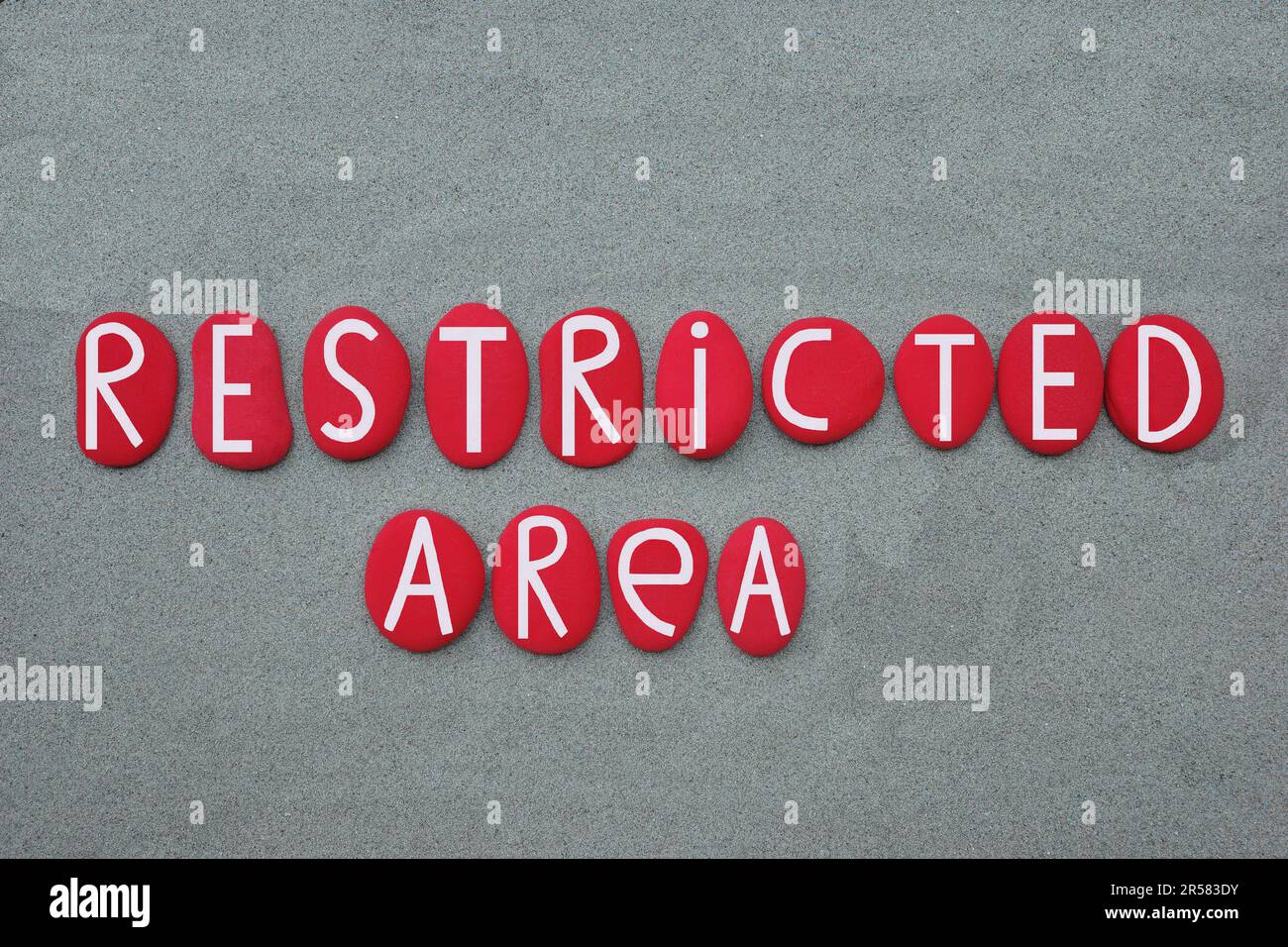 Restricted Area, red painted stone letters composed over beach sand Stock Photo