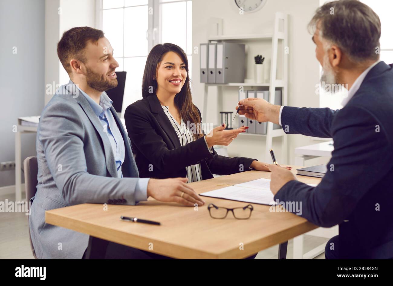 Real estate agent giving house keys to happy married couple Stock Photo ...