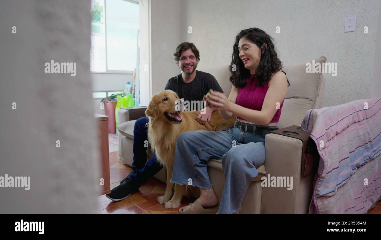 Couple sitting on couch playing with their Dog. Female Pet owner plays