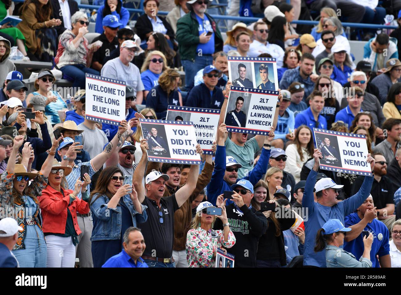 Family members hold up signs and cheer as diplomas are handed out