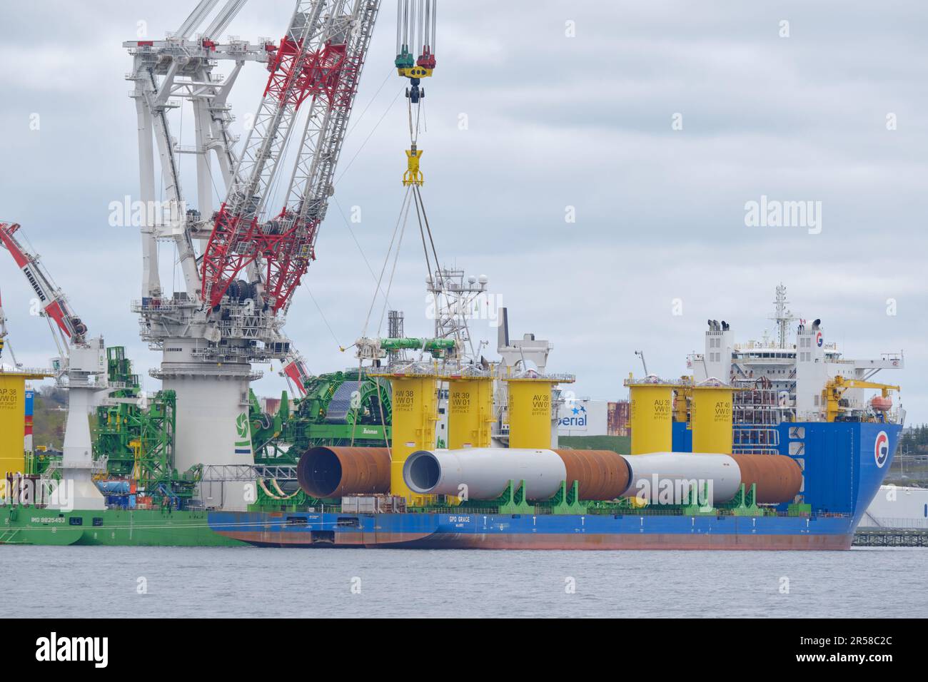 the Orion Offshore Heavy Lift crane moving wind turbine monopiles from the GPO Grace Stock Photo