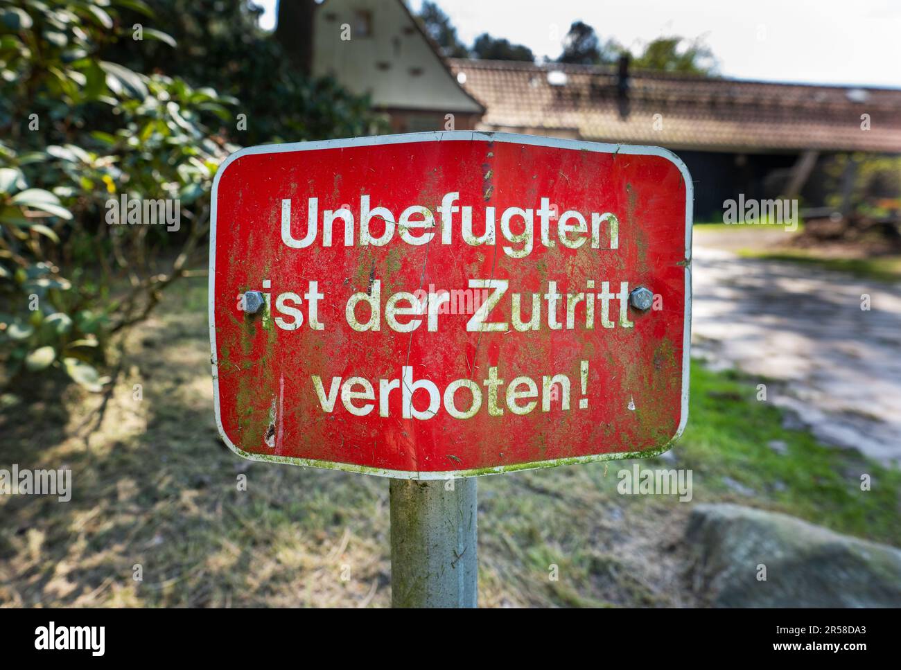 German red warning sign with the text 'Unauthorized persons are not allowed to enter' in front of country house. Stock Photo