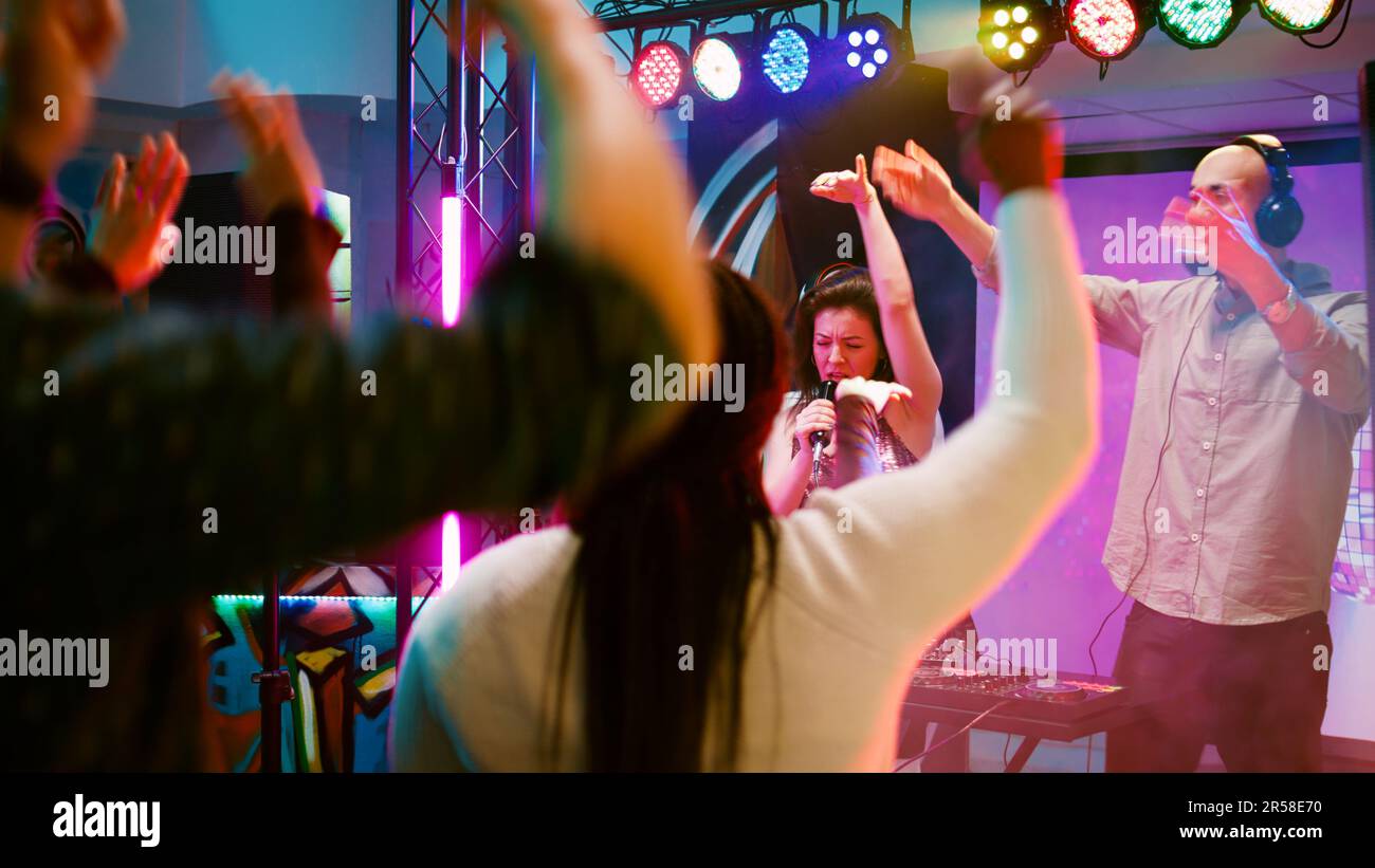 Happy woman doing karaoke at dance party, singing songs at microphone