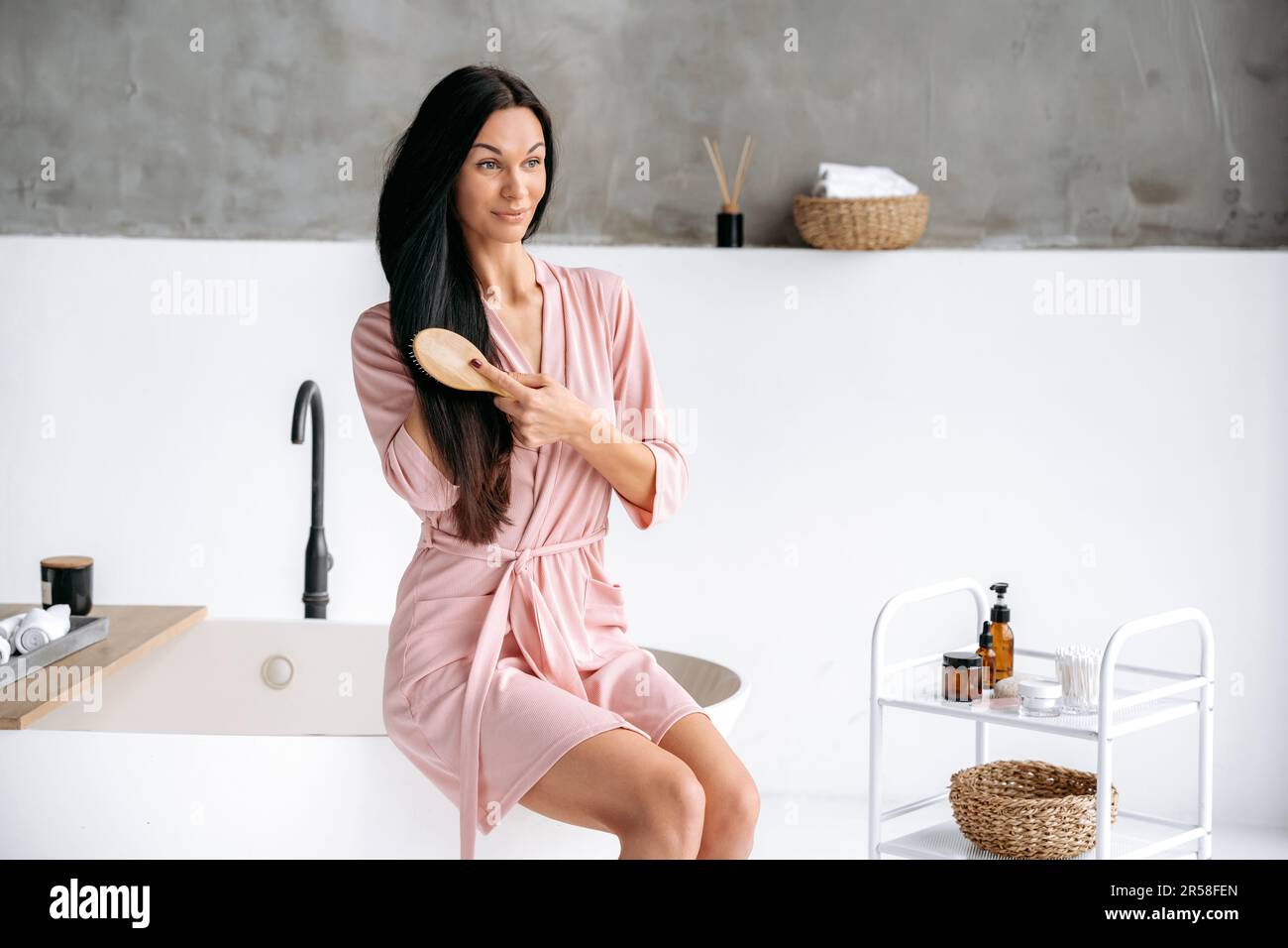 Bathrobe Routine Combing long hair. Beauty routine concept. Charming caucasian brunette ...